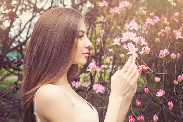 Beautiful woman face with clear skin profile Healthy girl sniffing flowers