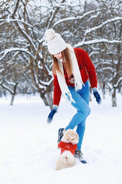 Beautiful woman in fashionable knitwear walking a dog