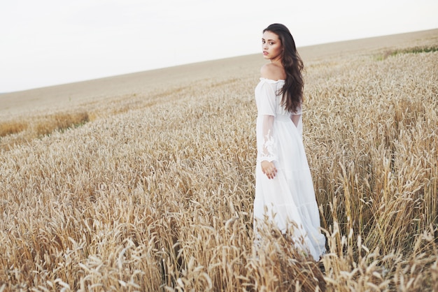 Beautiful woman in a field of wheat in a white dress, a perfect picture in the style lifestyle