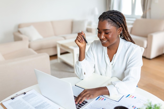 Beautiful woman freelancer noting information for planning project doing remote job via laptop computer woman laughing while reading email on modern laptop device