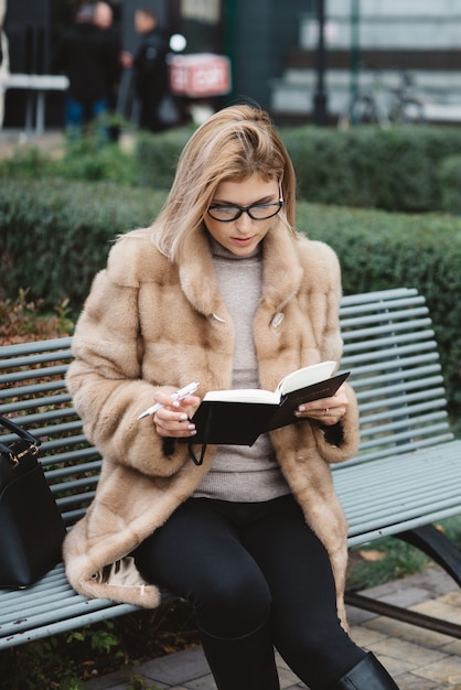 Beautiful woman in glasses and fur coat outdoor. 