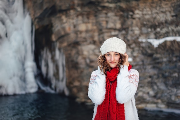 Beautiful woman in a hat and a long scarf posing in the cold