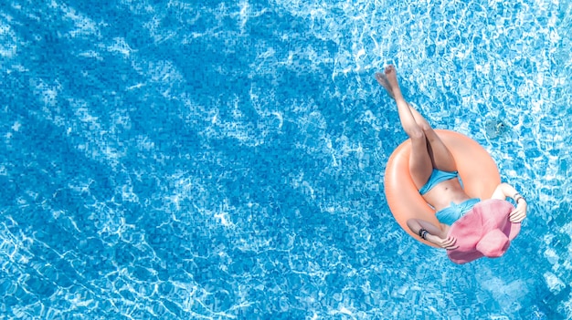 Beautiful woman in hat in swimming pool aerial top view from above young girl in bikini relaxes