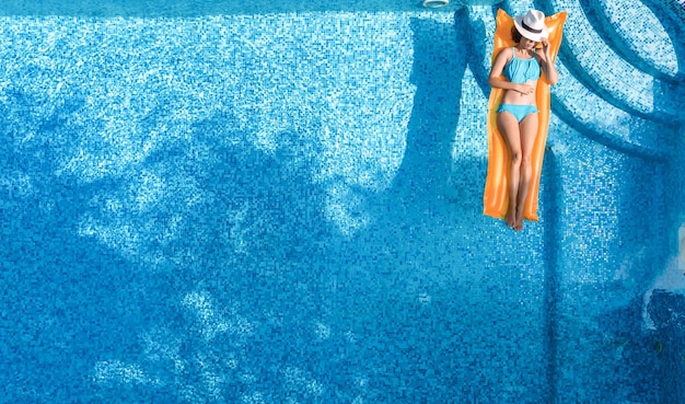 Beautiful woman in hat in swimming pool aerial top view from above young girl in bikini relaxes