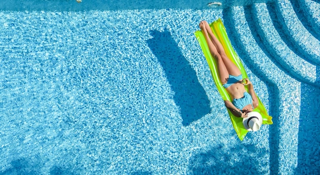 Beautiful woman in hat in swimming pool aerial top view from above young girl in bikini relaxes