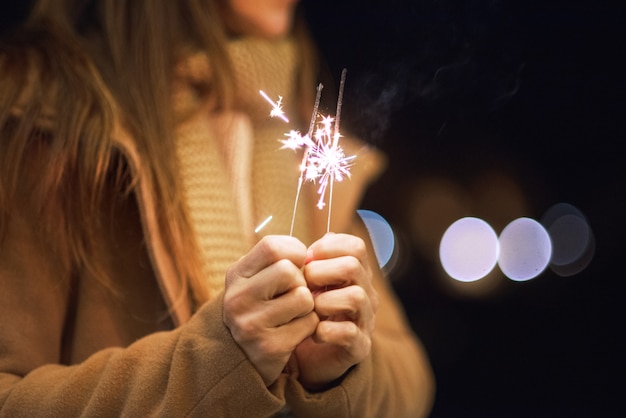 Photo beautiful woman having fun, with sparkler in her hands celebrating new year eve