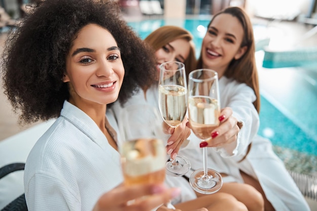 Beautiful woman and her two girlfriends holding champagne glasses