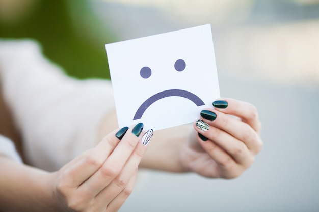 Beautiful woman holding card with sad smile