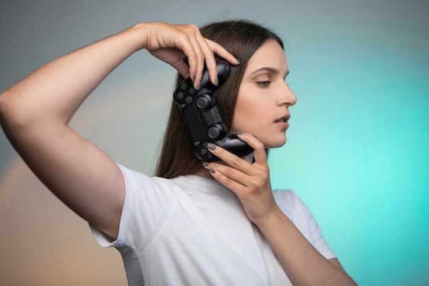 Beautiful woman holding console controller on colorful background. Young adult person enjoying