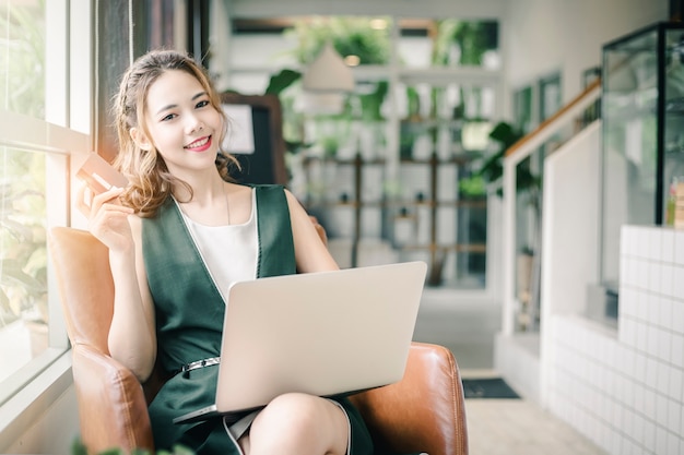 Beautiful woman holding credit card and shopping on laptop