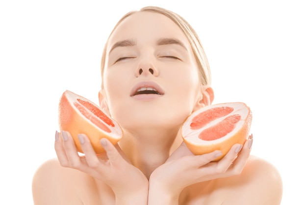 The beautiful woman holding a grapefruit on the white background