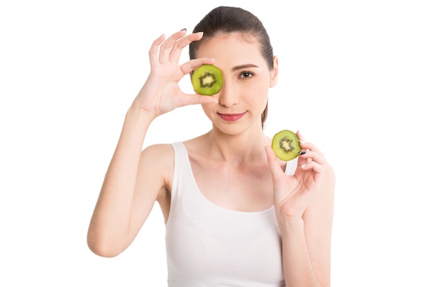 Beautiful woman holding kiwi slice hiding eye behind isolated on white background