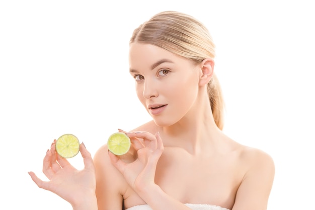 The beautiful woman holding two halves of a lime on the white background