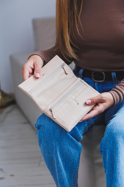 A beautiful woman holds a beige leather purse in her hands Small women's handbag