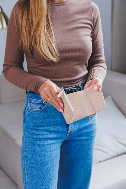 A beautiful woman holds a beige leather purse in her hands Small women's handbag