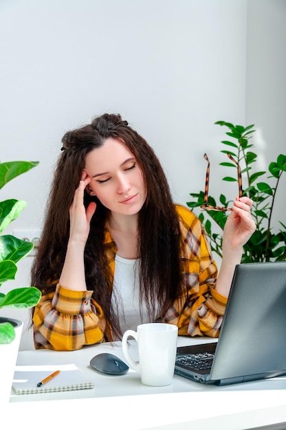 Beautiful woman holds her temples because of a headache or eye pain from working at a laptop woman