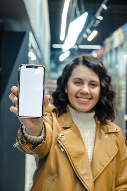 A beautiful woman holds a phone with a blank white screen in a grocery store