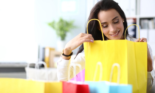 Beautiful woman is amazed to see gift in shopping bag