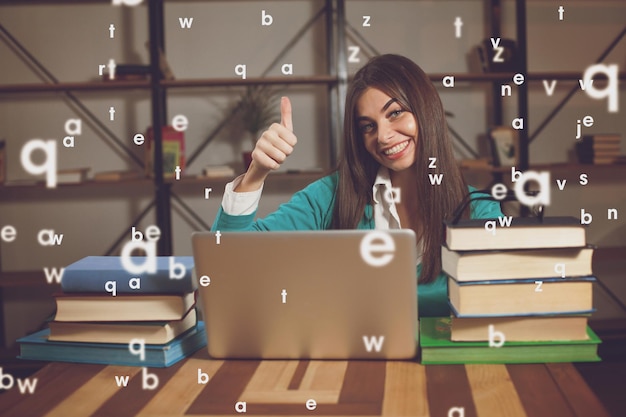 Beautiful woman is happy about her successful work with laptop at the wood table