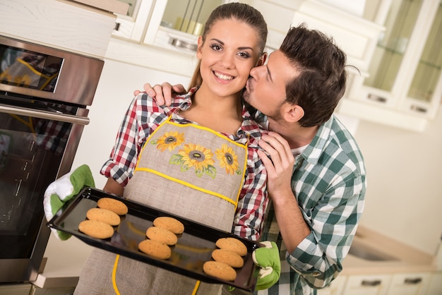 Beautiful woman is holding hot roasting pan with cookies.