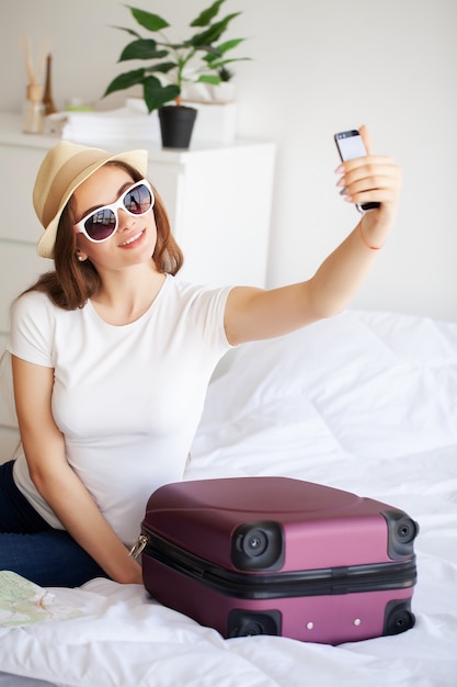 Beautiful woman is packing clothing in suitcase at home.