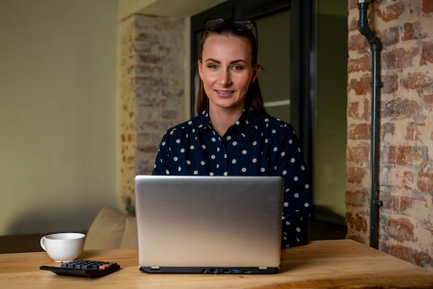 Beautiful woman is working on a laptop computer late at night A young creative manager feels happy looks at the camera and smiles