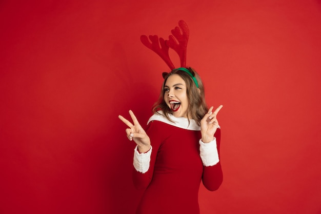 Beautiful woman like christmas deer isolated on red surface concept of  new years winter mood holidays