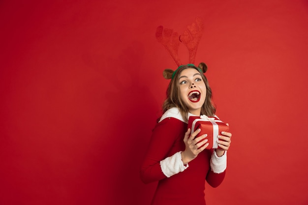 Beautiful woman like christmas deer isolated on red wall concept 