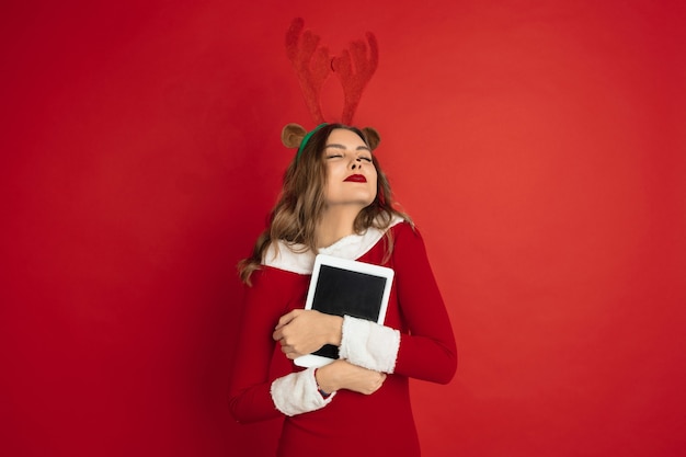 Beautiful woman like christmas deer isolated on red wall