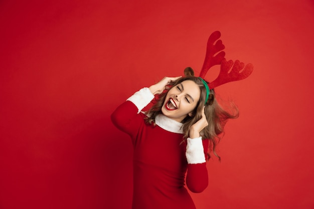 Beautiful woman like christmas deer isolated on red wall