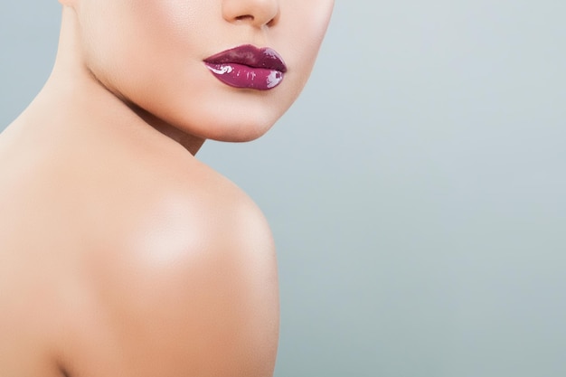 Beautiful woman lips with purple glossy lipstick and lipgloss on background with copy space