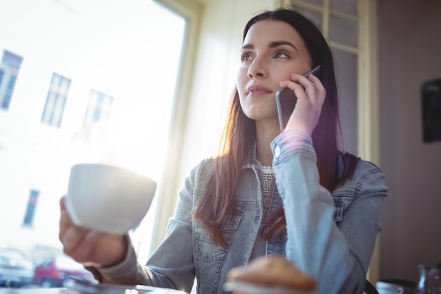 Beautiful woman listening to cellphone at coffee shop