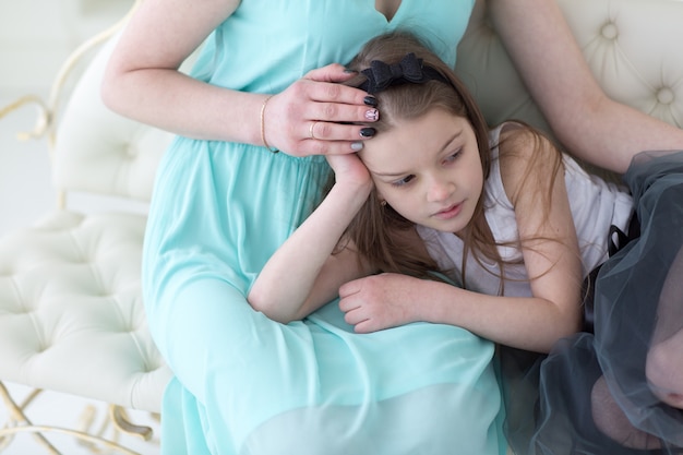 Beautiful woman in navy greek dress with daughter on knees