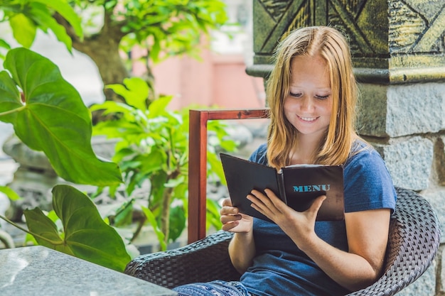 Beautiful woman ordering from menu in restaurant and deciding what to eat