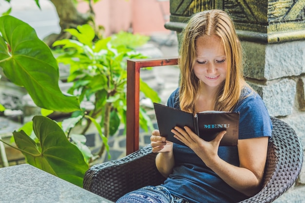 Beautiful woman ordering from menu in restaurant and deciding what to eat