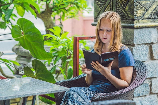 Beautiful woman ordering from menu in restaurant and deciding what to eat