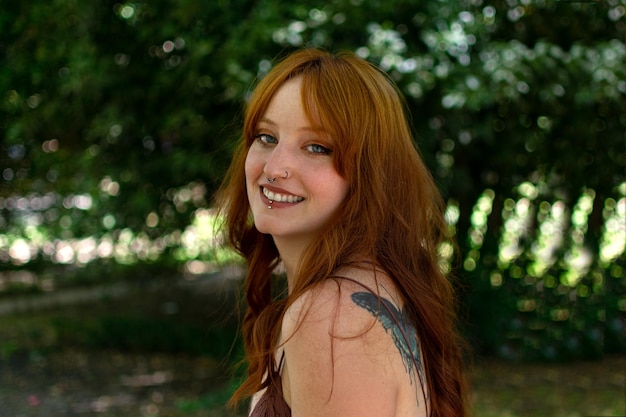 A beautiful woman outdoors in a green park laughs and smiles as she looks into the camera at sunset