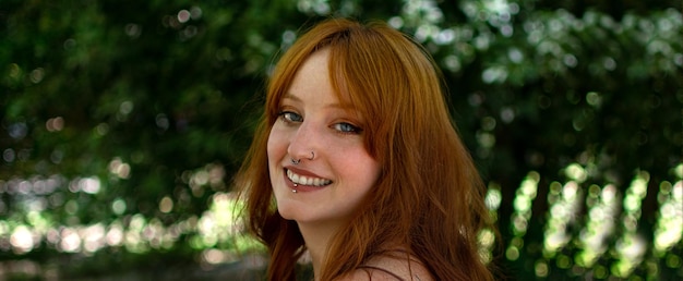 A beautiful woman outdoors in a green park laughs and smiles as she looks into the camera at sunset