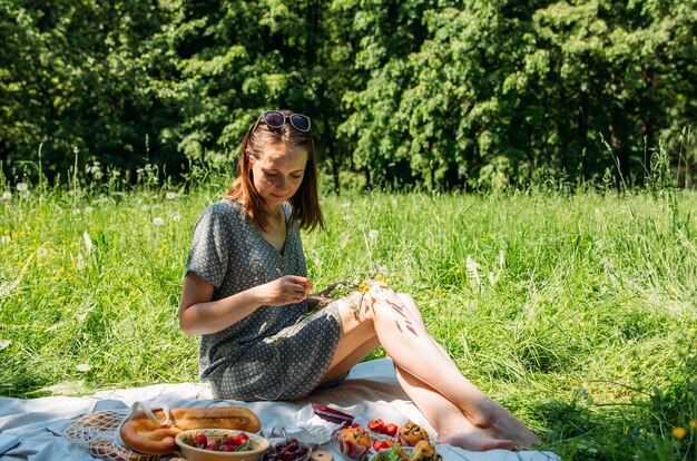 Beautiful woman on picnic she smiles eats strawberries and enjoys summer