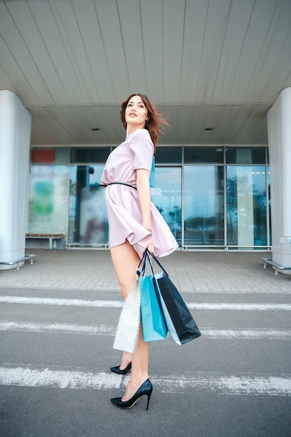 Beautiful woman in a pink dress with shopping bags