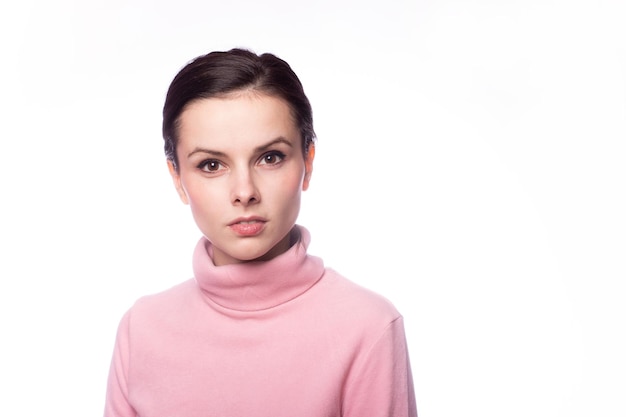 beautiful woman in a pink turtleneck on a gray background