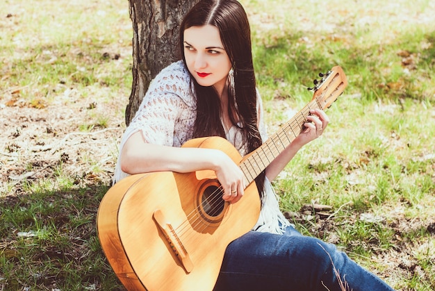 Beautiful woman playing an acoustic guitar outdoor