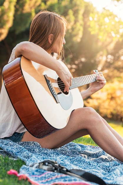 Beautiful woman playing guitar in the park.