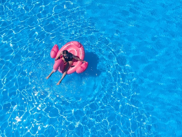 Beautiful woman in pool with flamingo pool float in hotel