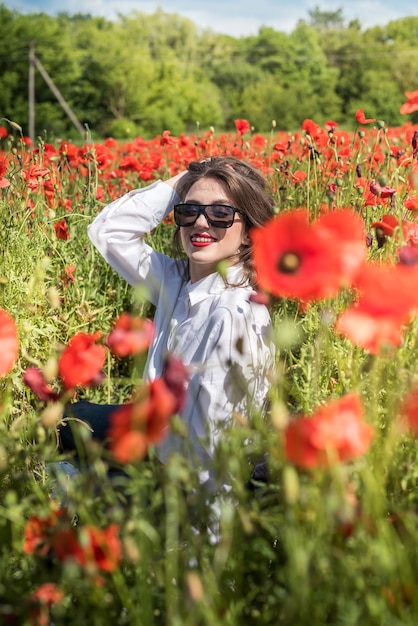 Beautiful woman in a poppy field, enjoy summer time. Romantic mood nature lover