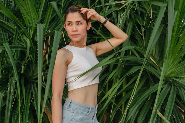 Beautiful woman pose on green palm bush for photography in summer concept