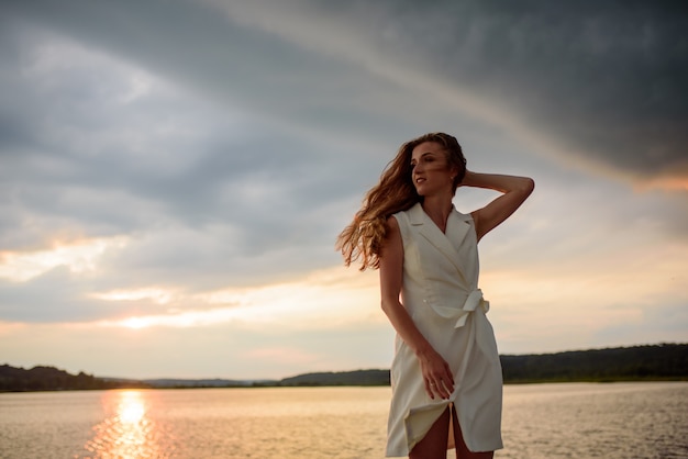 Photo beautiful woman posing by the lake at sunset