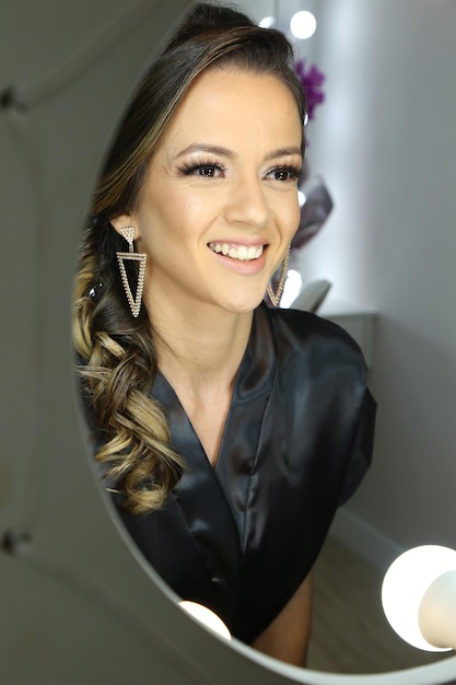 Beautiful woman putting on makeup in front of the mirror for a party