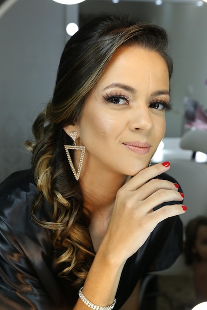 Beautiful woman putting on makeup in front of the mirror for a party