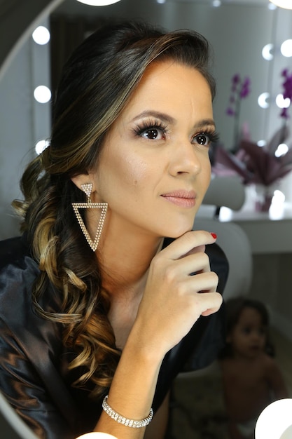 Beautiful woman putting on makeup in front of the mirror for a party